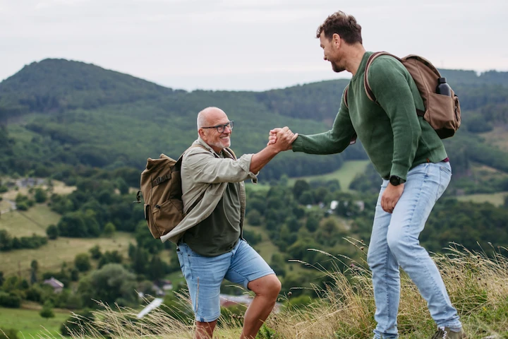 Older man staying active with support on a mountain trail